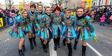 Group of women in colorful dresses posing at a festive street event.