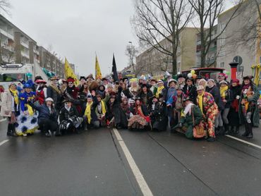 Large group in colorful costumes posing on a street during a celebration.