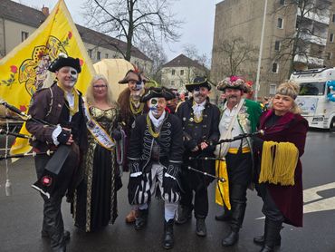 Group dressed in pirate-themed costumes with face paint and gold beads at an outdoor event.