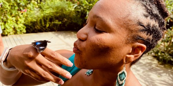 Woman gently interacts with a butterfly on her finger.