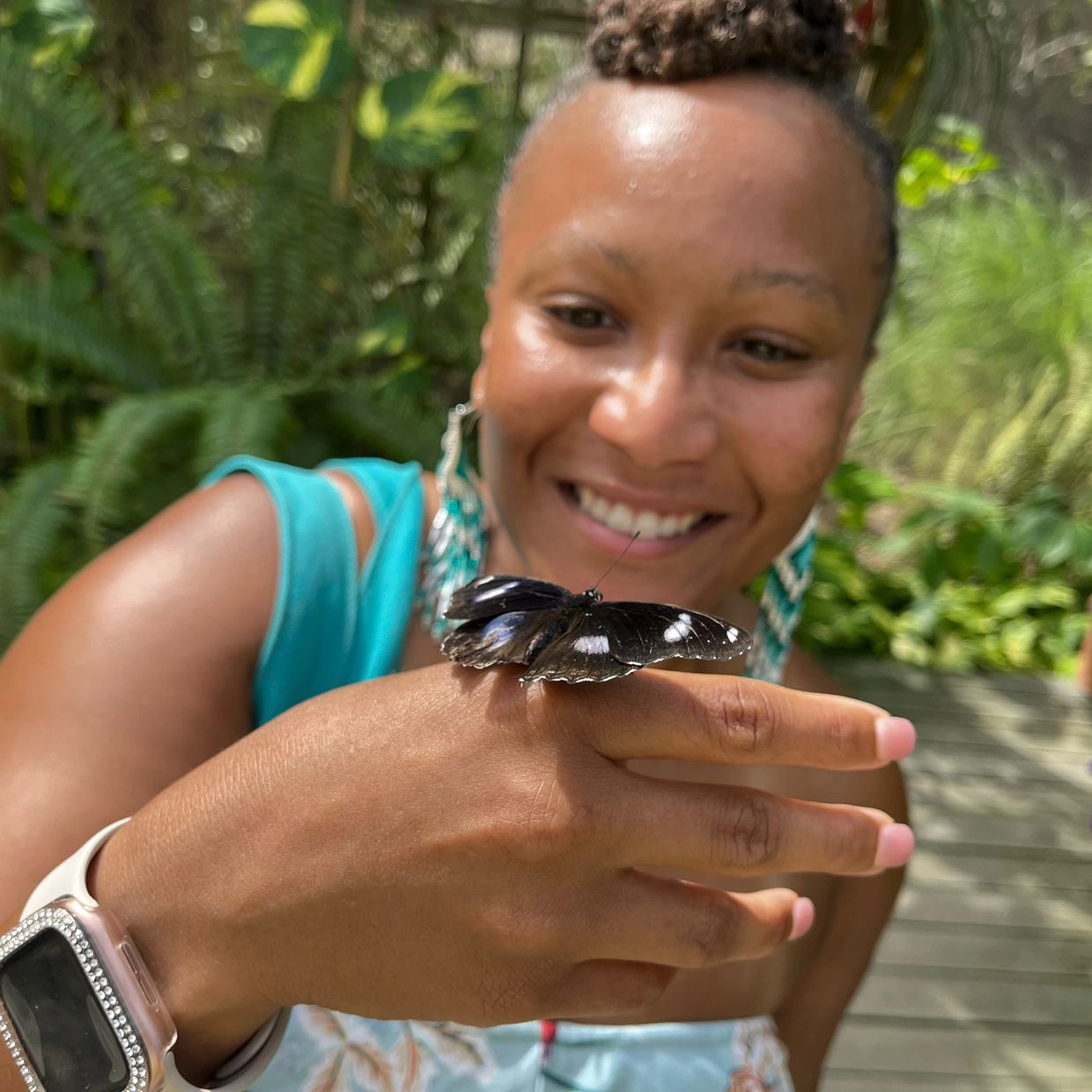 Woman with butterfly on her hand smiling.