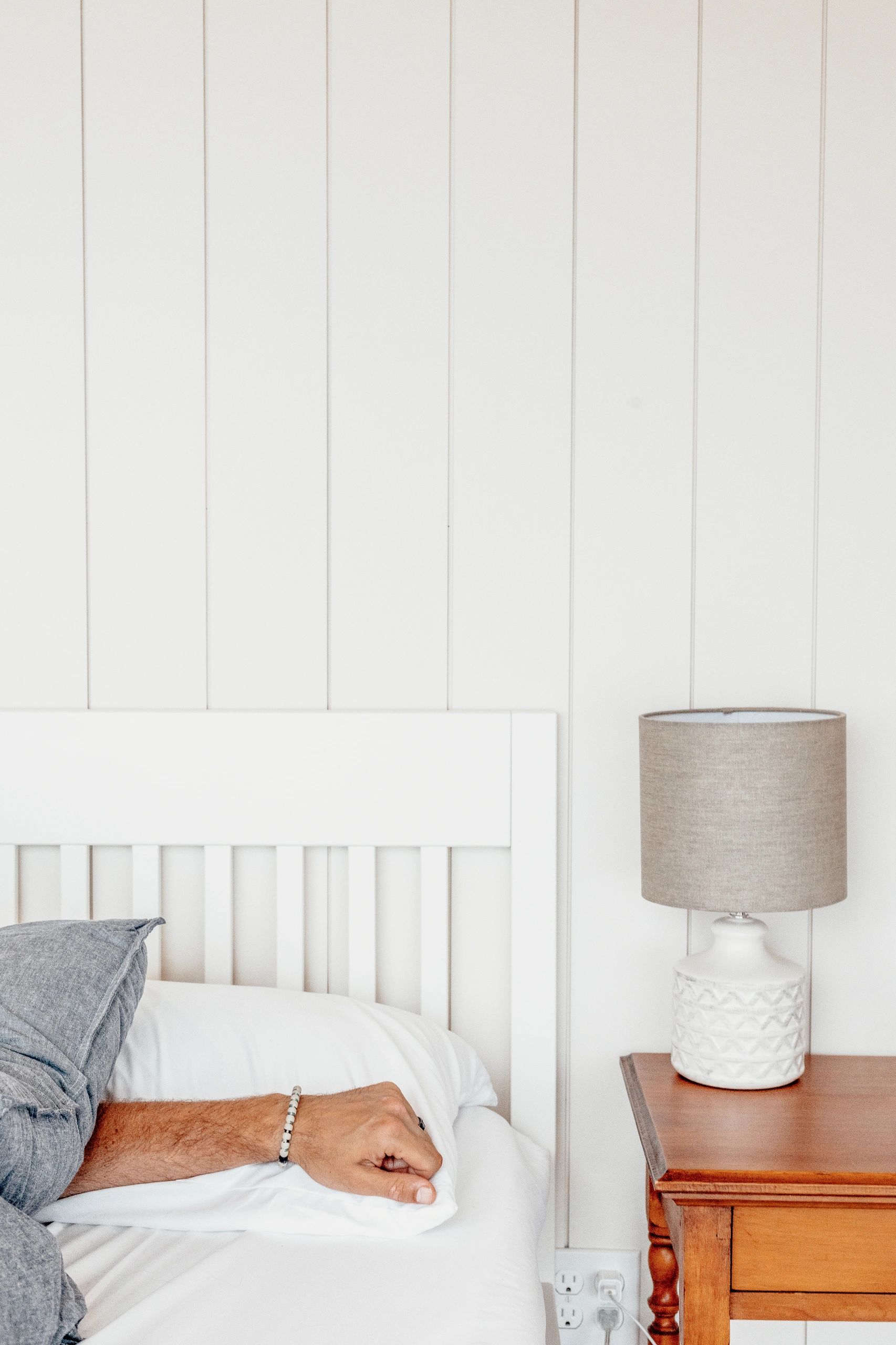 Man's arm in a cozy oceanfront glamping dome in Nova Scotia with shiplap wall, antique side table 