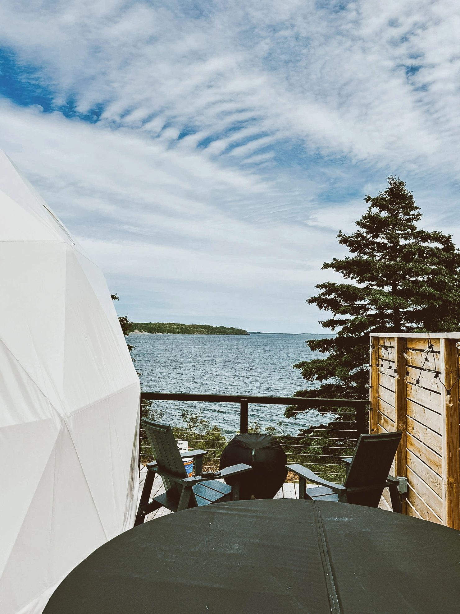 Private glamping dome deck with hot tub, fire pit, sitting area and ocean views in Nova Scotia