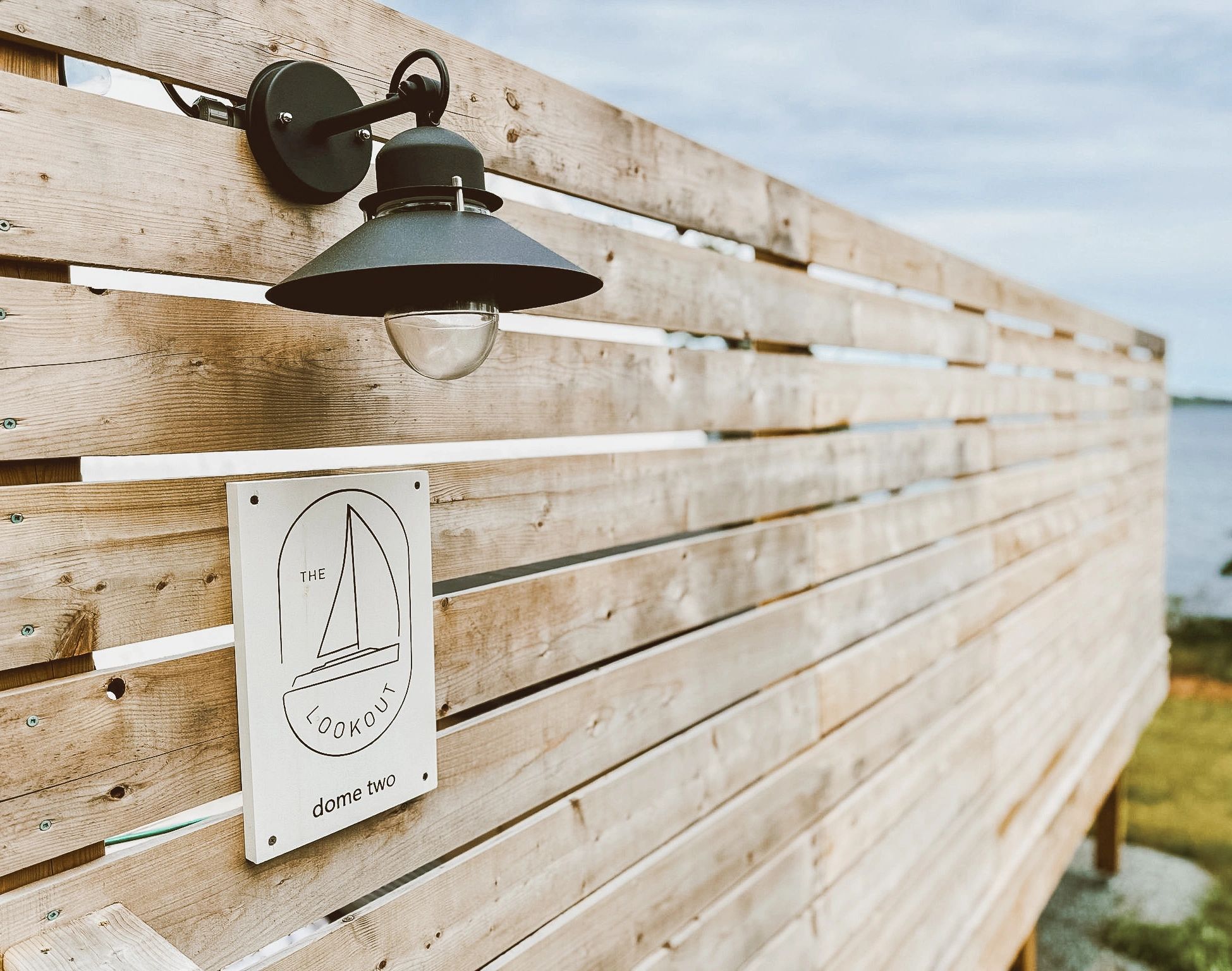 A light and a sign on the exterior of the private deck connected to a Nova Scotia glamping dome.