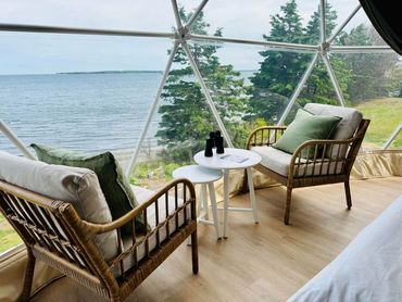 nova scotia dome seating area with two chairs, coffee tables and tree lined ocean view