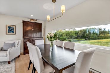 nova scotia cottage dining area with antique hutch, table, chairs. large picture with forest view.