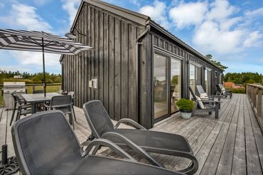 nova scotia cottage on sunny day. lounge chairs and table with umbrella on deck.