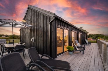 nova scotia cottage in the evening with lounge chairs, muskoka chairs and expansive deck.