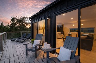 nova scotia cottage in the evening. exterior with lights on. muskoka chairs.