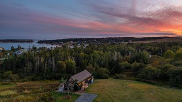 nova scotia cottage aerial view. modern barn home. ocean view. next to forest.