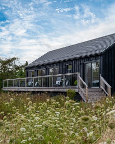 nova scotia cottage exterior. modern barn home with expansive deck. wildflower lawn.