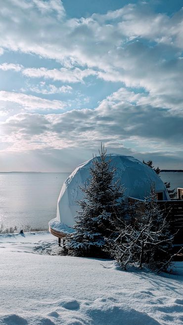 Nova scotia glamping dome during winter time with snow on ground overlooking ocean