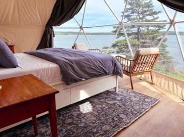 NS Dome bedroom with bed, sitting area, rug and ocean view