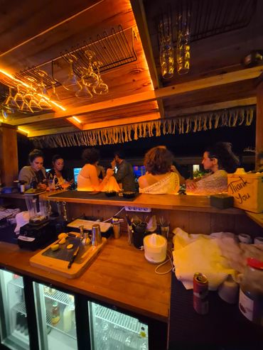 Friends enjoying drinks together at a cozy, warmly lit bar at night.