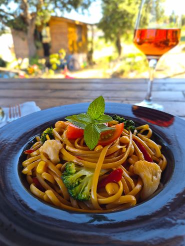 Colorful vegetable stir-fried noodles served in a black bowl.