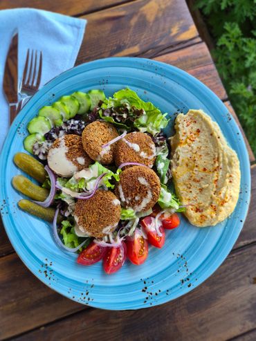 Falafel salad with hummus and fresh vegetables on a blue plate.