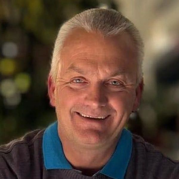 Smiling middle-aged man with gray hair and blue eyes.