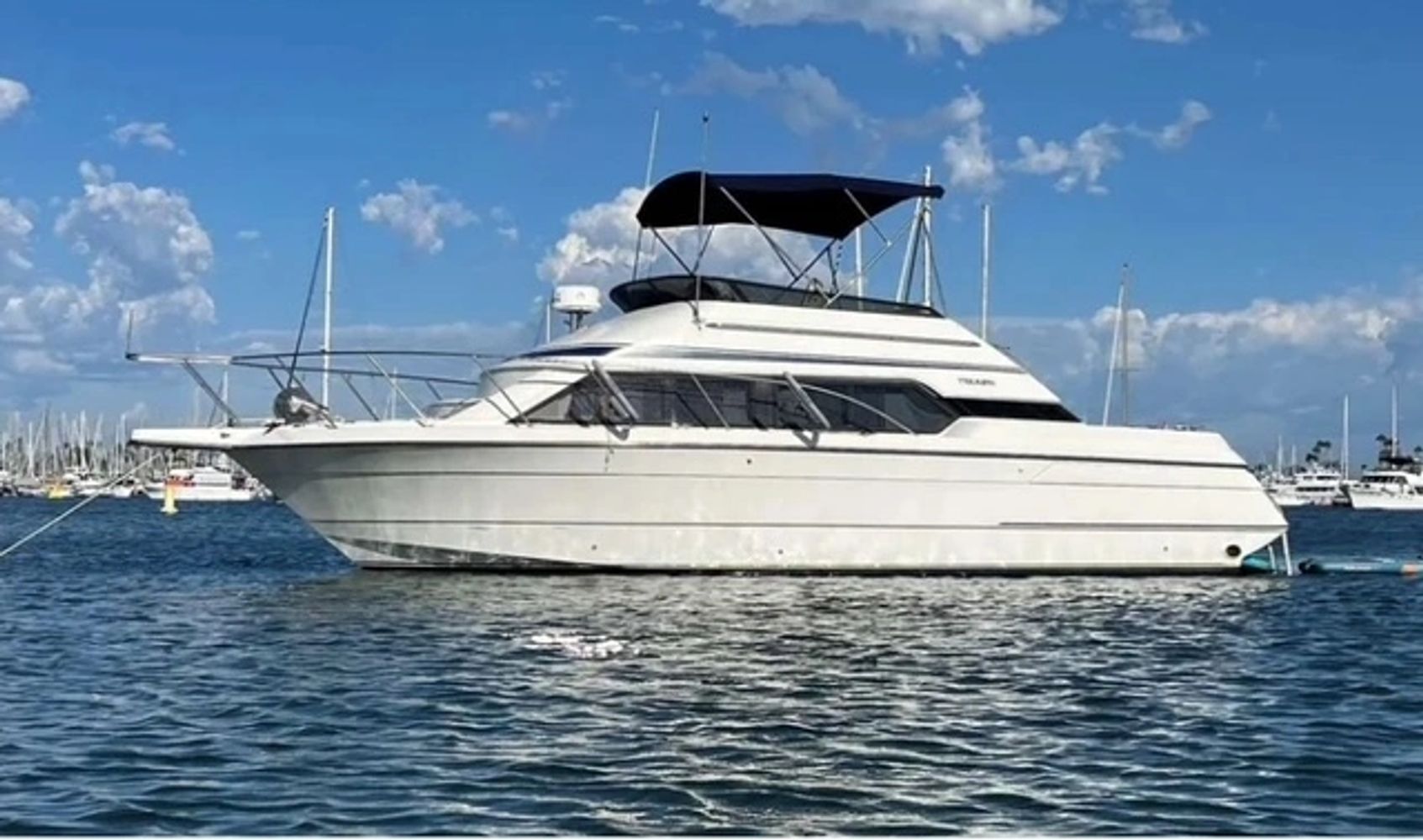 White luxury motor yacht floating on calm sea with blue sky.
