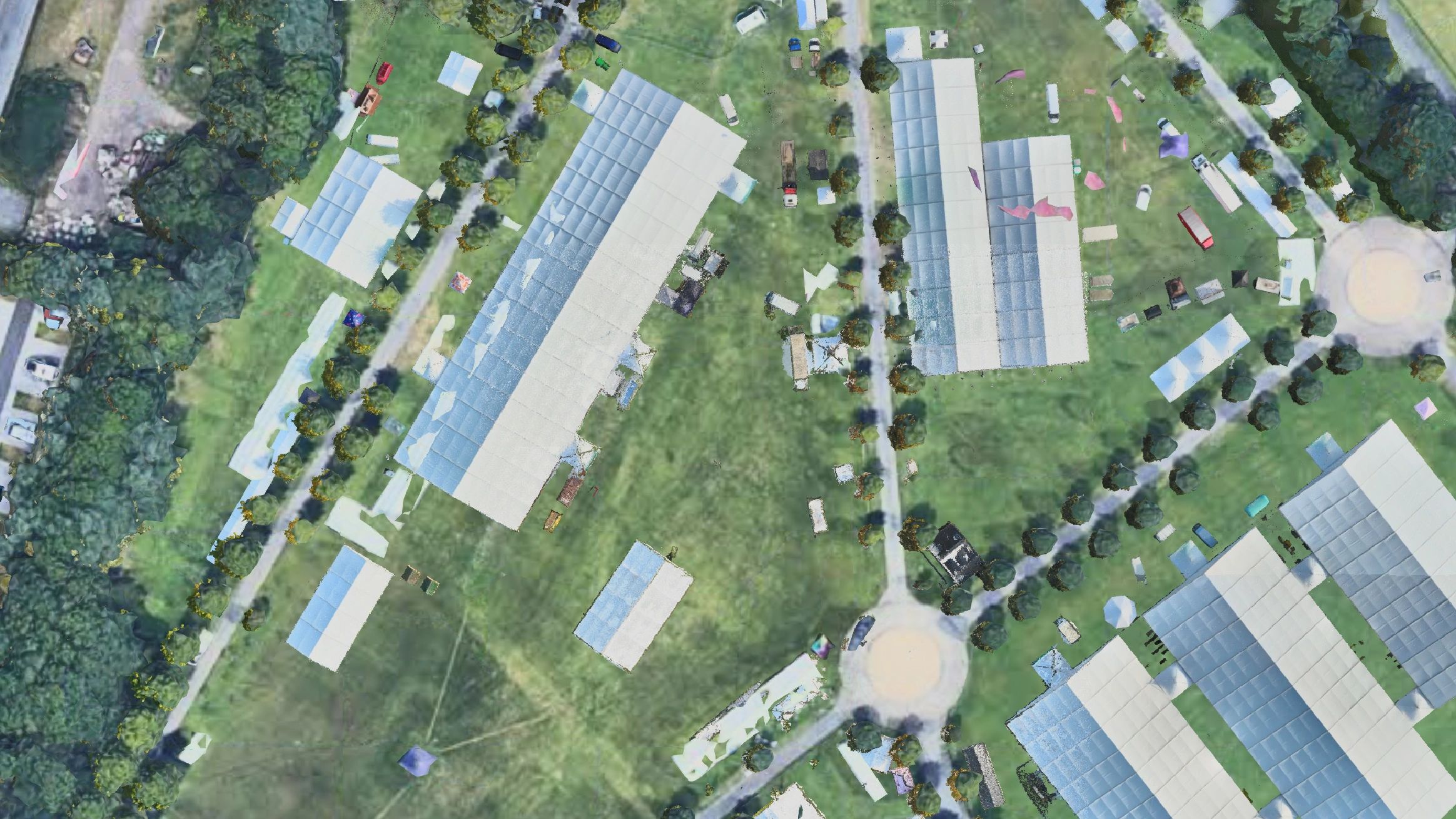Aerial view of a large outdoor event with multiple white tents and greenery.