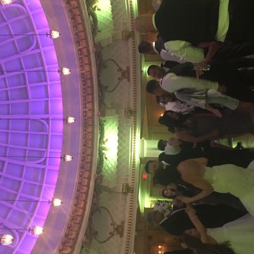 People dancing under a decorative dome ceiling with purple lights.