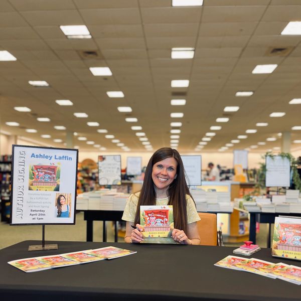 Author Ashley Laffin at a book signing event holding her book.