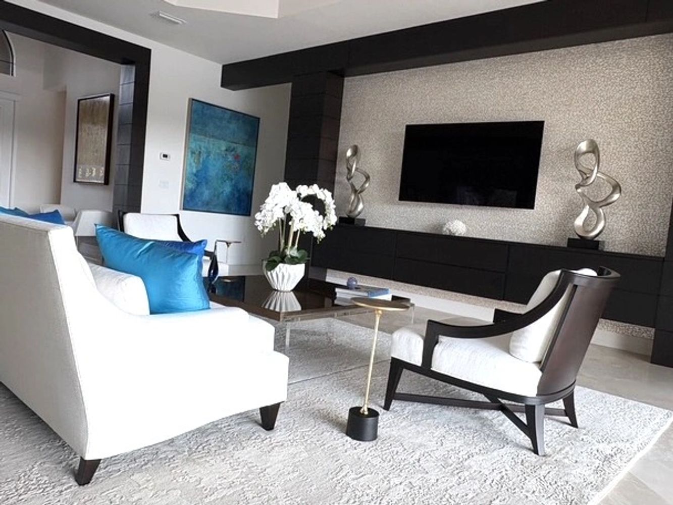 Modern living room with white furniture and blue accents.