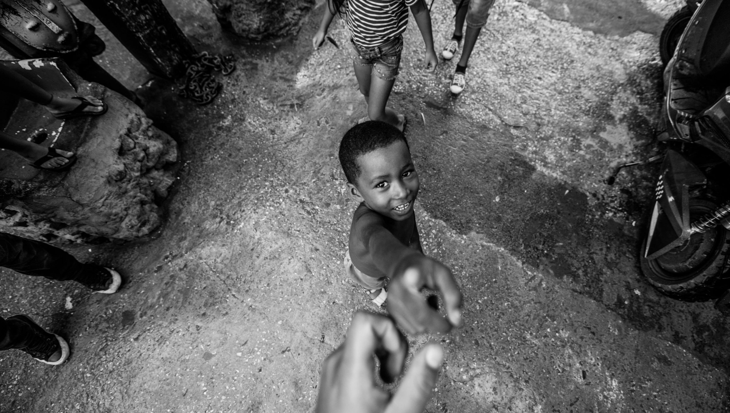 Boy reaching up smiling, black and white street photo.