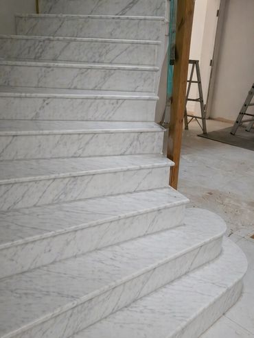 Elegant white marble stairs with a rounded bottom step.
