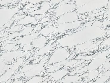 Large white marble slab with intricate gray veining on a wooden stand.
