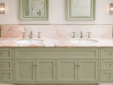 Elegant double sink bathroom vanity with green cabinetry and marble countertop.