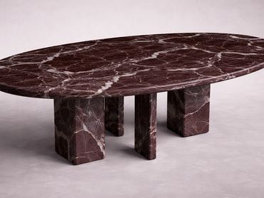 Oval marble table with thick legs on a light floor.
