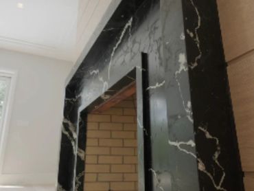 Black marble fireplace with white veins in a modern room.