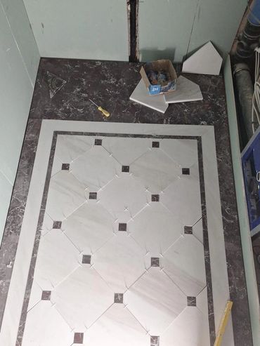 Intricate floor tiling in progress with white and brown marble tiles.