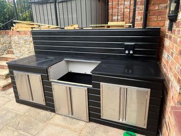 Outdoor black cabinet with stainless steel doors and an open section.