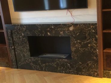 Modern black marble fireplace with a mounted TV above.