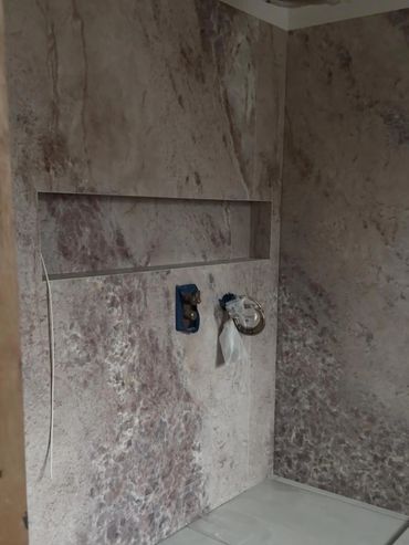 Wall with marble-like texture and recessed shelf under construction.