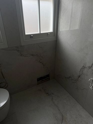 Modern bathroom with marble walls and frosted window.