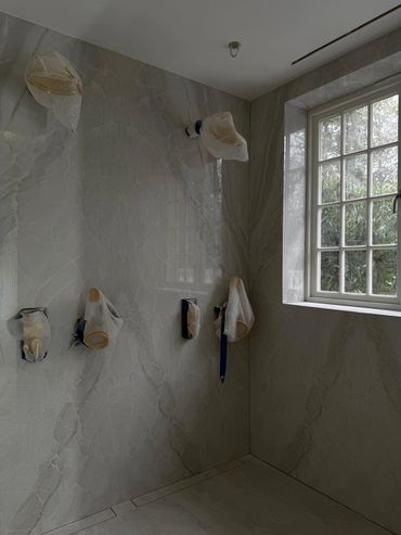Bathroom fixtures covered for painting or renovation beside a window.