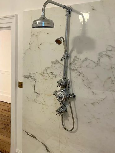 Elegant chrome shower fixture on marble wall in a minimalist bathroom.