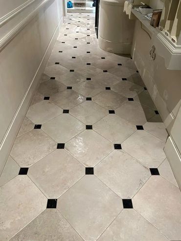 Hallway floor with beige tiles and small black square accents.