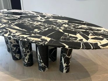 Black and white marble oval table with cylindrical legs.