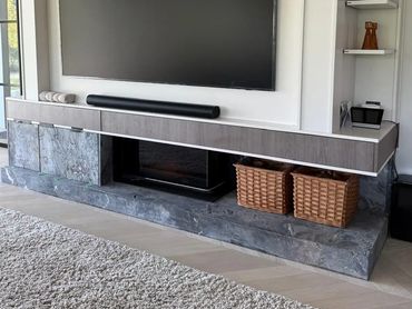 Modern living room setup with a floating TV console and stone accents.