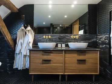 Modern bathroom with double vessel sinks and wood cabinetry.