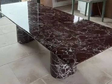 Rectangular dark marble table with cylindrical legs on tiled floor.
