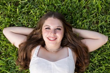 Young woman smiling lying on grass.