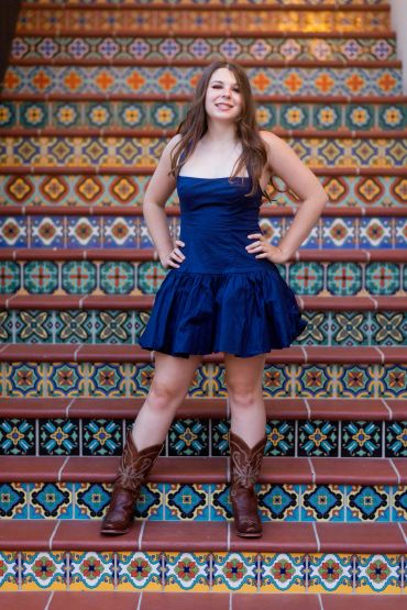 Young woman in blue dress and boots on colorful tiled stairs.
