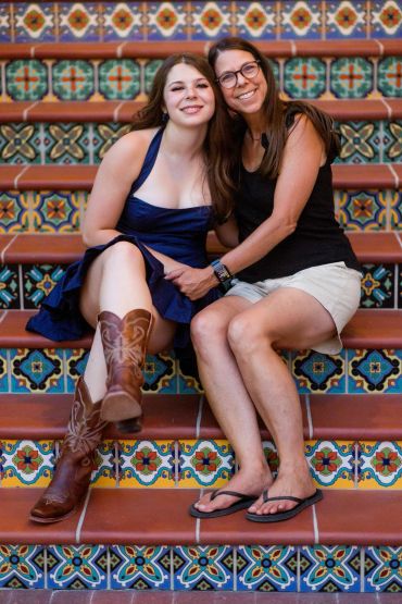 Two women sitting on colorful tiled stairs, smiling.