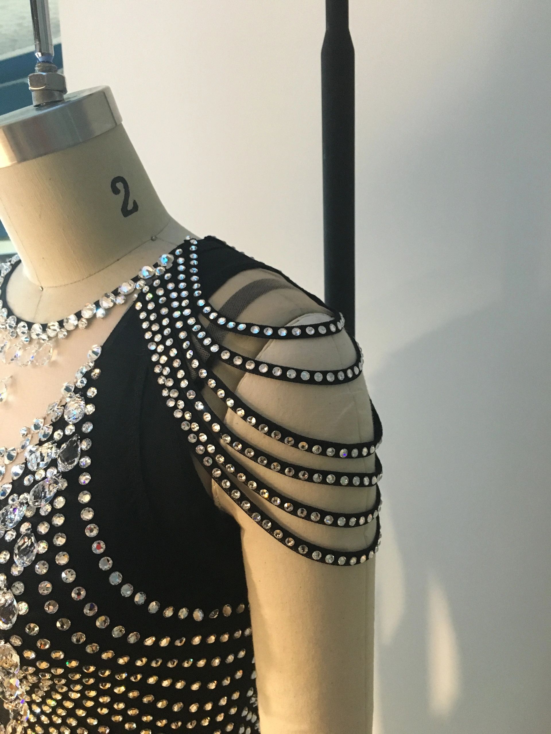 Black garment adorned with rhinestones on a mannequin.
