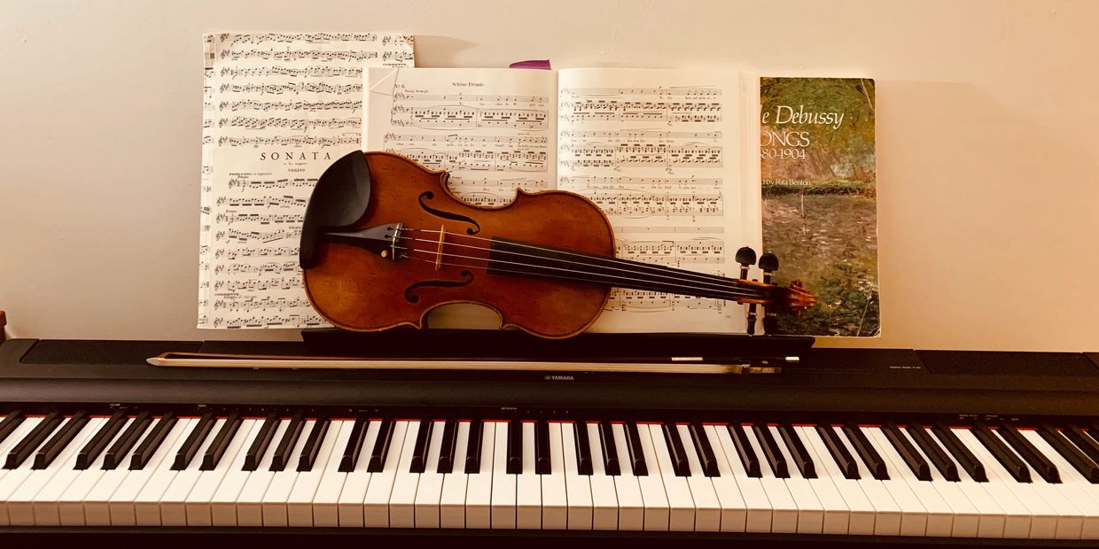 Violin and sheet music on a digital piano