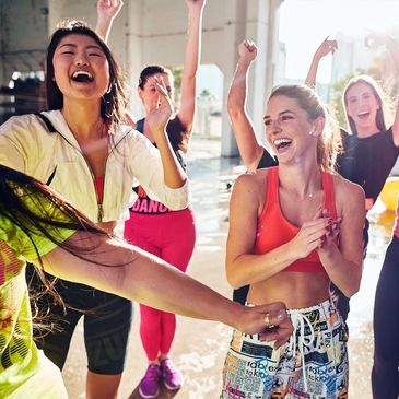 A group of young women smiling and dancing together.